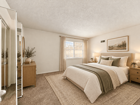 A bedroom with a large bed and a wooden nightstand.