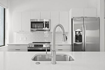 a white kitchen with stainless steel appliances and a sink
