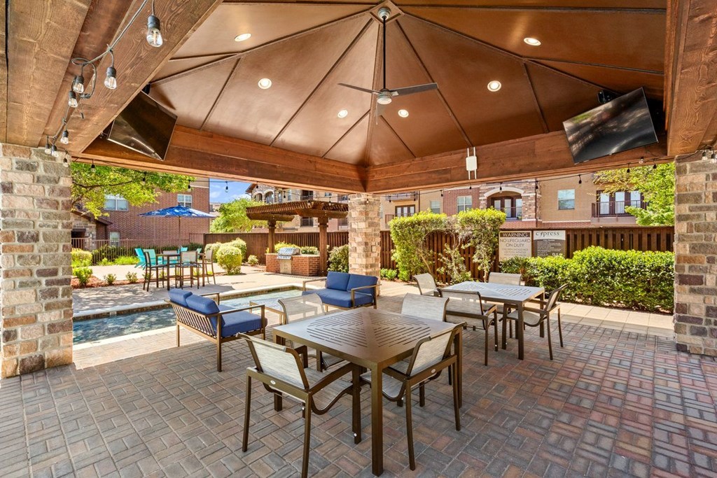 a patio with tables and chairs and a pool at Cypress at Lewisville Apartment Homes, Lewisville, TX