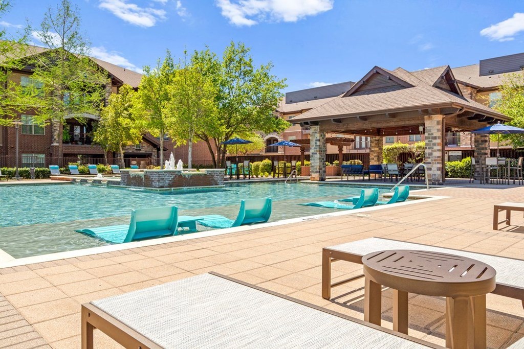a swimming pool with lounge chairs and a table at Cypress at Lewisville Apartment Homes, Lewisville
