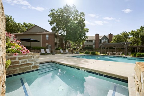 Community pool with lounge chairs, stone accents, and landscaped surroundings.