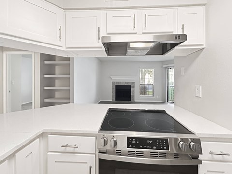 A modern kitchen with white cabinets and a stainless steel stove top.