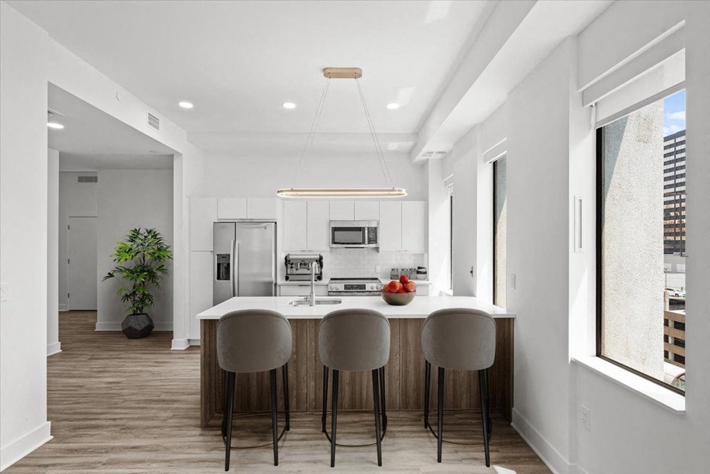 A modern kitchen with a bar stool and a dining table. at Sky On Main Apartments, Missouri City, MO, 64105