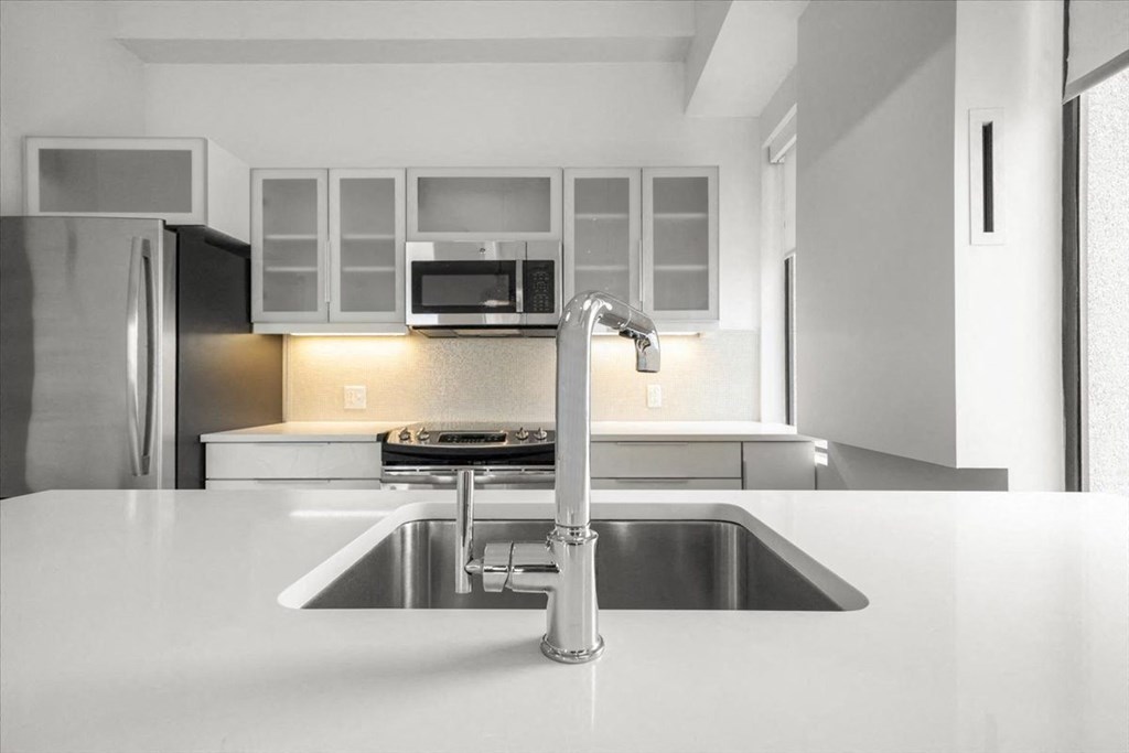 A modern kitchen with a stainless steel refrigerator and a white countertop at Sky On Main Apartments, Missouri City, MO