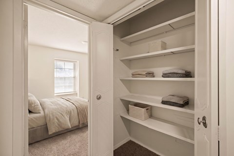 Spacious closet with built-in shelving and hanging space located next to a bedroom at Louisburg Square Apartments in Overland Park, KS.