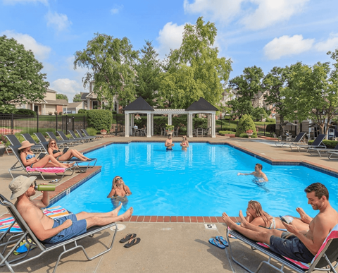 People are relaxing by the pool on a sunny day.