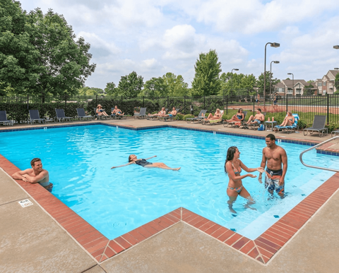 A group of people are enjoying a sunny day at the pool.