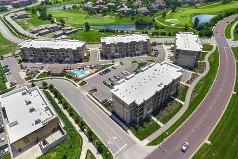 A large apartment complex with a pool and a golf course in the background.