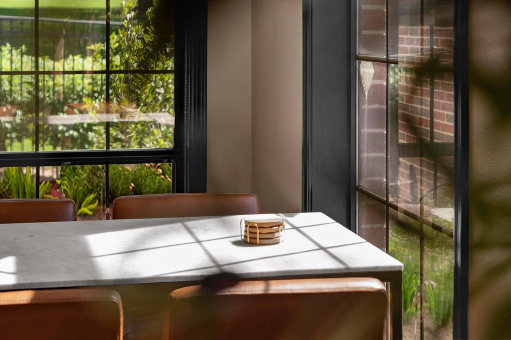 A table with a basket on it is in front of a window with a view of a garden. at Highland Park Apartment Homes, Kansas
