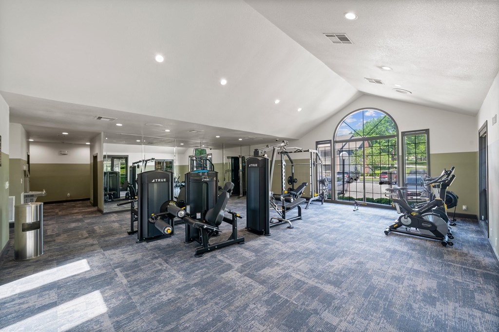 A spacious gym with a variety of equipment and a large window. at Highland Park Apartment Homes, Kansas