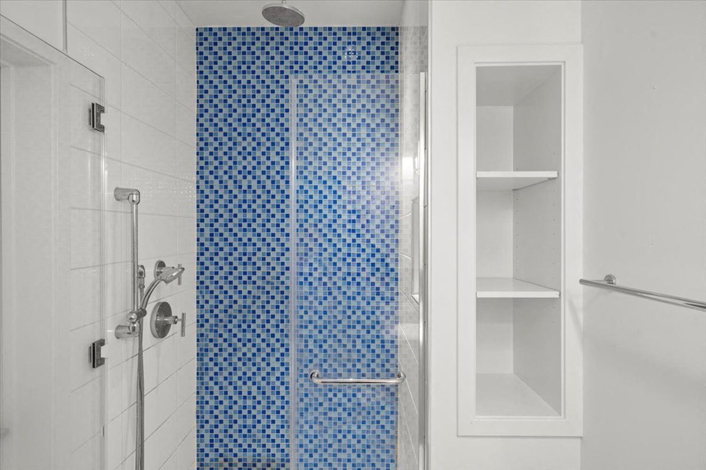A white bathroom with a blue tiled shower at Sky On Main Apartments, Missouri City, MO
