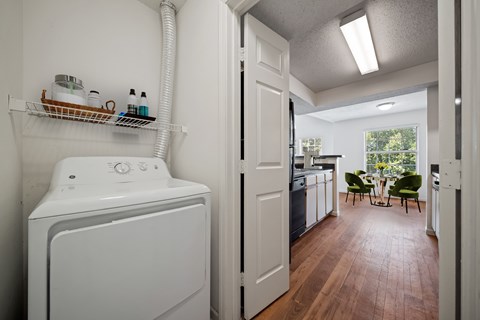 In-unit laundry area with dryer and shelving at Stonebriar Apartments in Overland Park Kansas