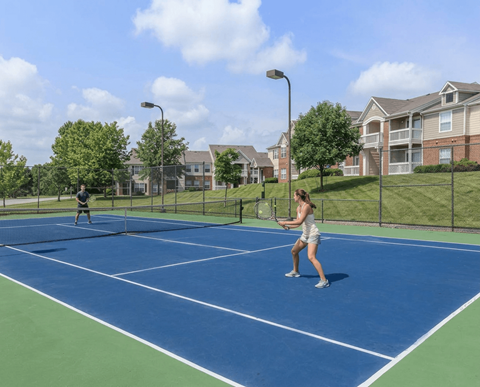 Two people playing tennis on a blue court.