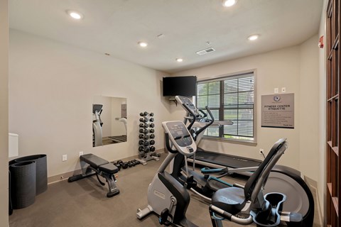 Fitness center at The Dorset with cardio machines, free weights, and workout bench