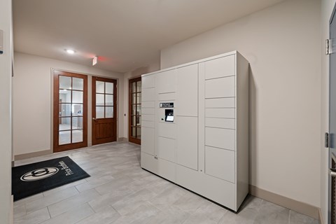 A white cabinet with a black handle is in a room with a black mat on the floor.