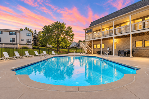 A large swimming pool in front of a building with a balcony.