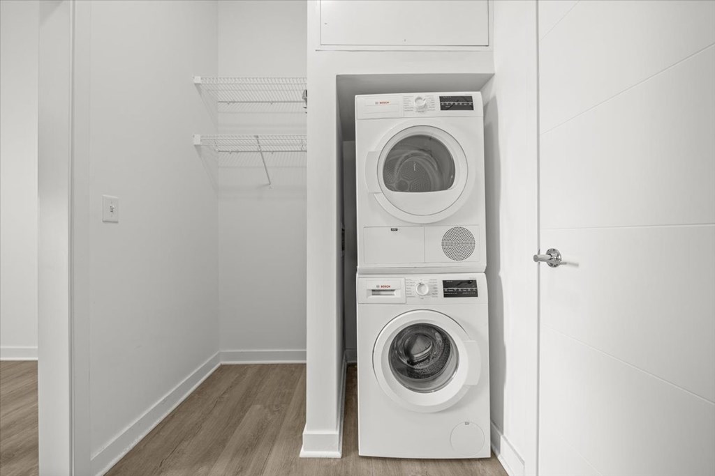 A white washing machine and dryer in a small laundry room at Sky On Main Apartments, Missouri City, Missouri