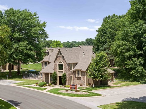 A house with a stone facade is surrounded by green trees.