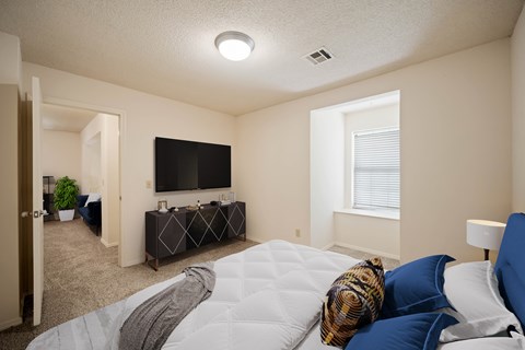 A bedroom with a bed, a couch, a television, and a window.