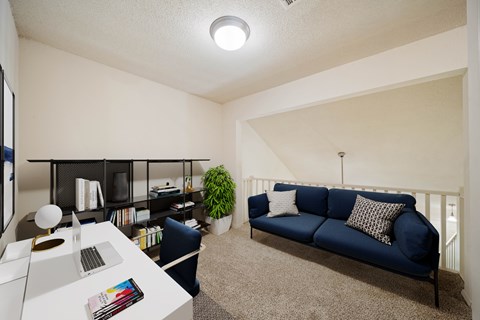 A blue couch sits in a living room with a white table and a plant.