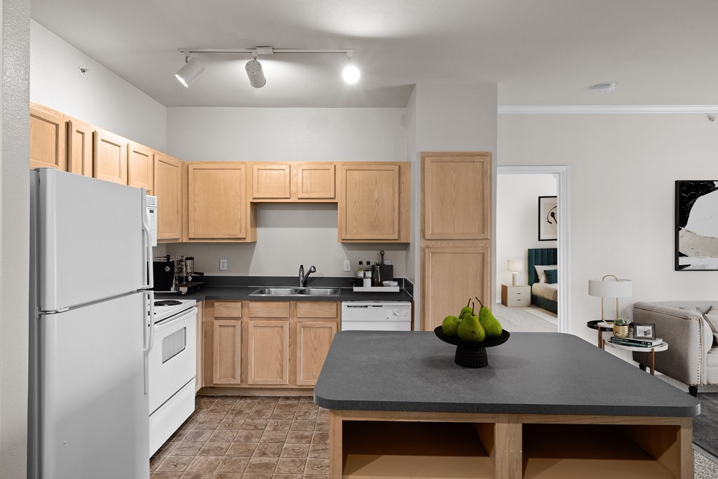 Kitchen A kitchen with oak cabinets, white appliances, track lighting and a kitchen island with storage.