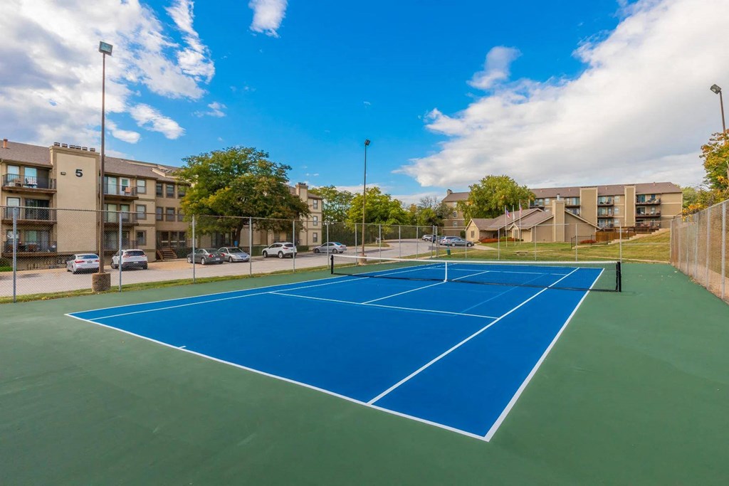 a pickleball court with apartments in the background at Cloverset Active Adult Apartments, Kansas City