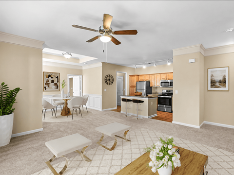 A living room with a ceiling fan and a dining table with chairs.