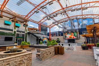 a view of the outdoor seating area with a water fountain in the foreground and a large screen