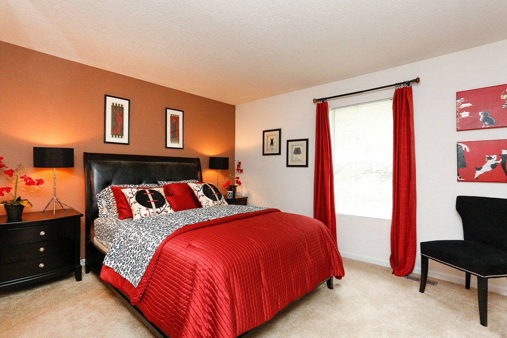 a bedroom with a bed and a window with red curtains