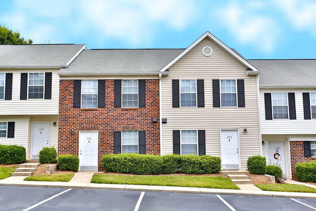 the front of a beige house with black shutters and a lawn