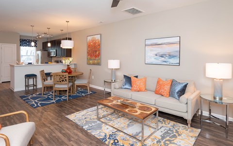A living room with a white couch, a wooden coffee table, and a painting on the wall.