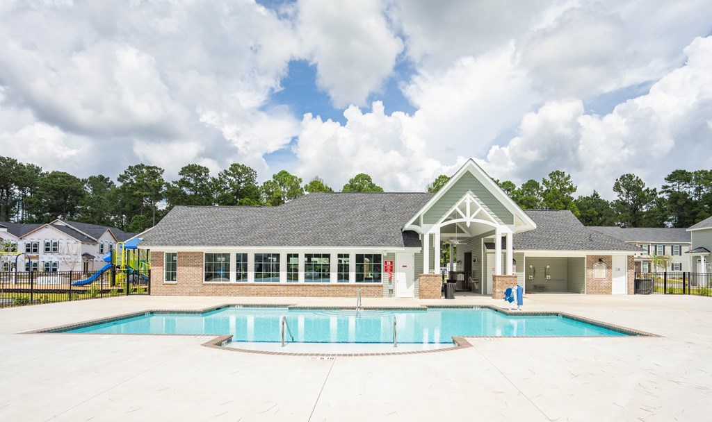 A pool area with a building and a slide in the background.