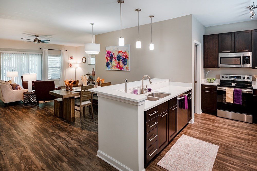 A kitchen with a white counter top and wooden floors.