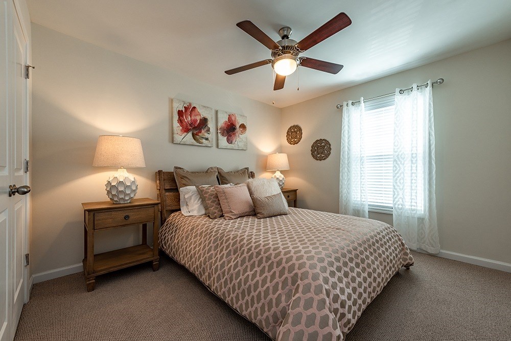 A bedroom with a bed, nightstand, and a ceiling fan.