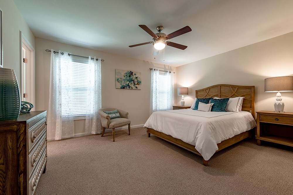 A bedroom with a large bed and a ceiling fan.