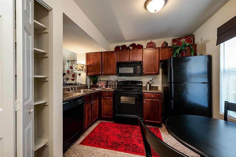 A kitchen with a black refrigerator and wooden cabinets.