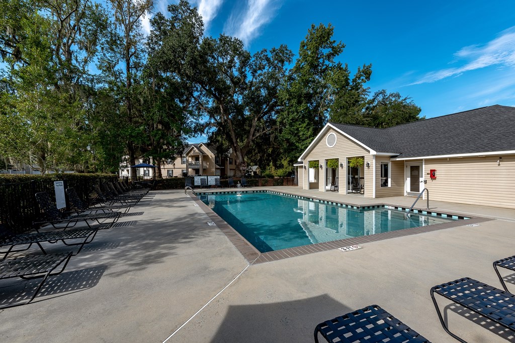 A pool area with a small building and trees in the background.