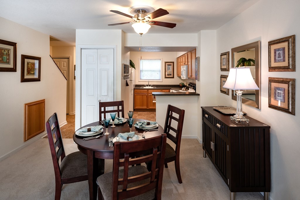 A dining room with a table set for two and a ceiling fan.
