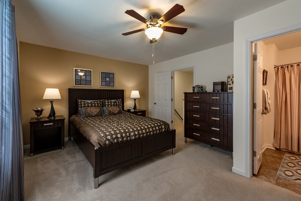 A bedroom with a bed, dresser, and ceiling fan.
