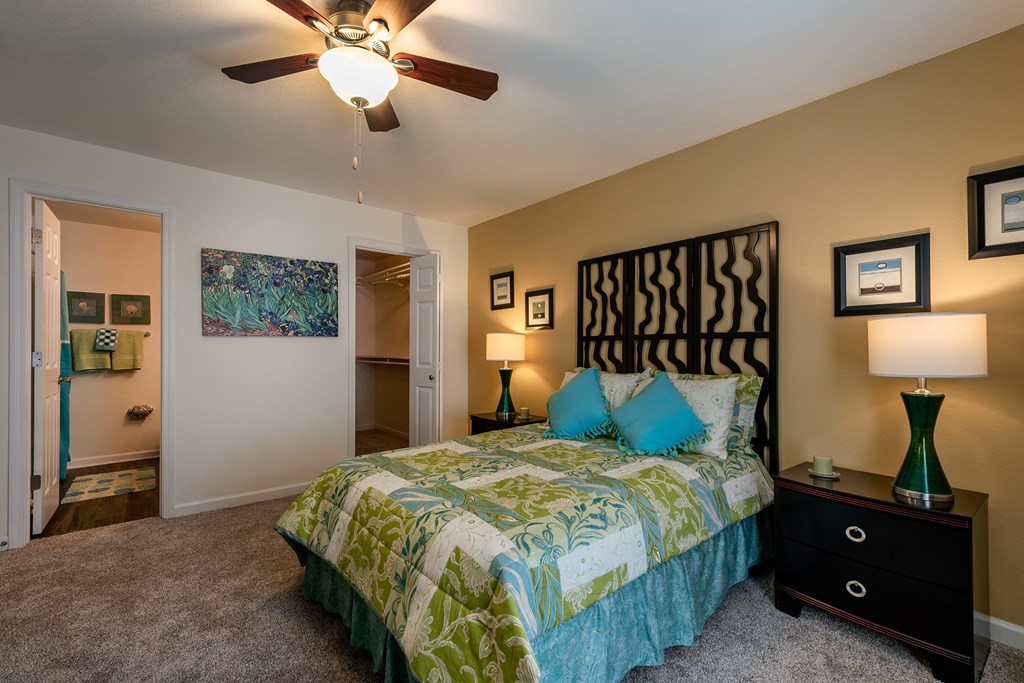 A bedroom with a bed, nightstand, and a ceiling fan.