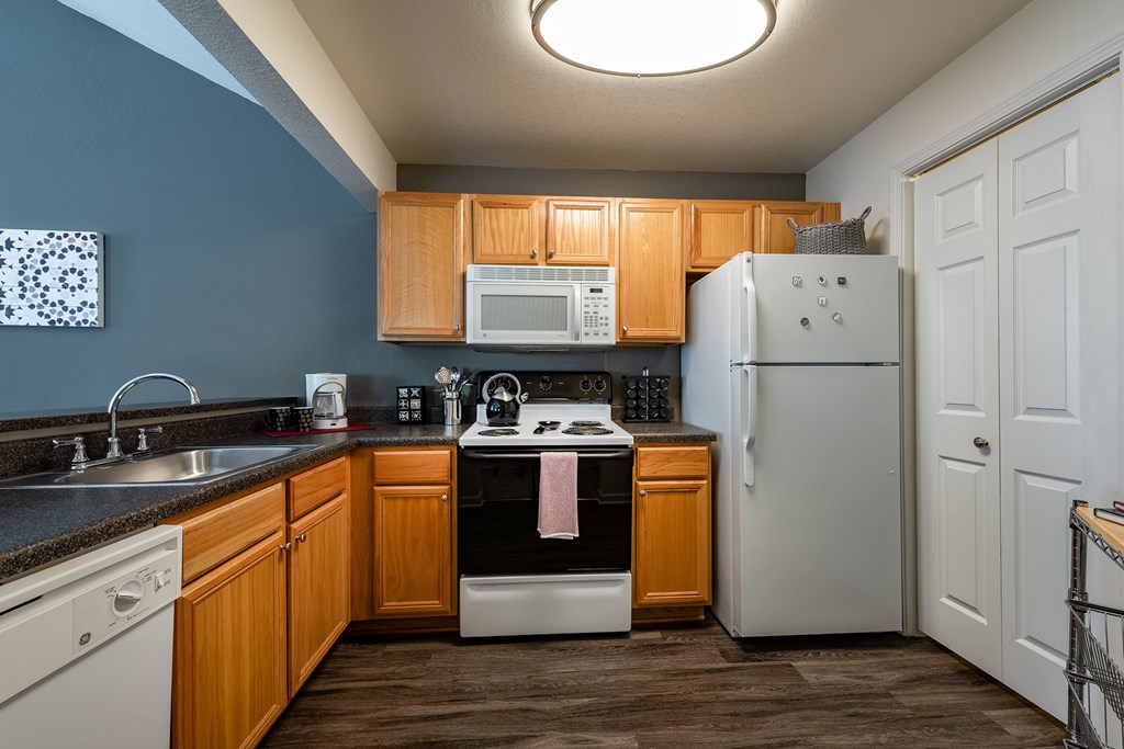 A kitchen with a white refrigerator and wooden cabinets.