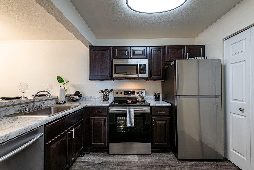 A kitchen with dark brown cabinets and stainless steel appliances.