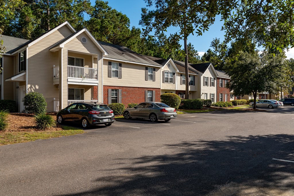 A car is parked in front of a two-story apartment building.