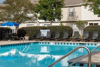 a swimming pool with chairs and a house in the background