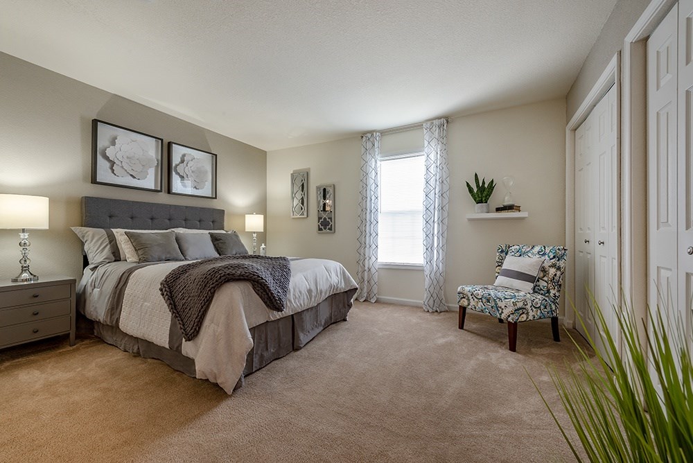 A bedroom with a bed, chair, and two framed pictures on the wall.
