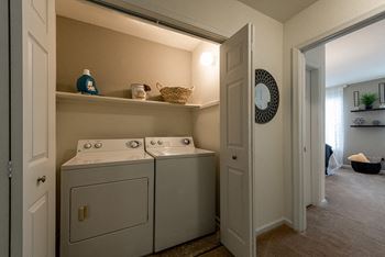 a laundry room with a washer and dryer and a door to a bedroom