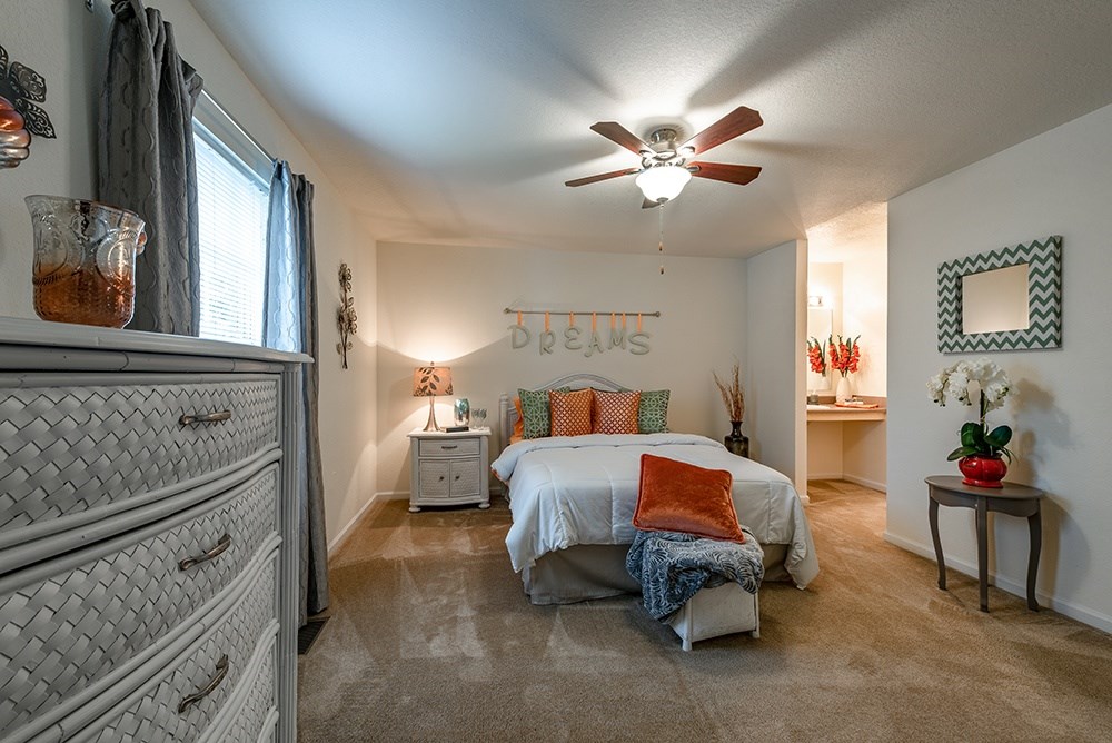 A bedroom with a bed, dresser, and ceiling fan.