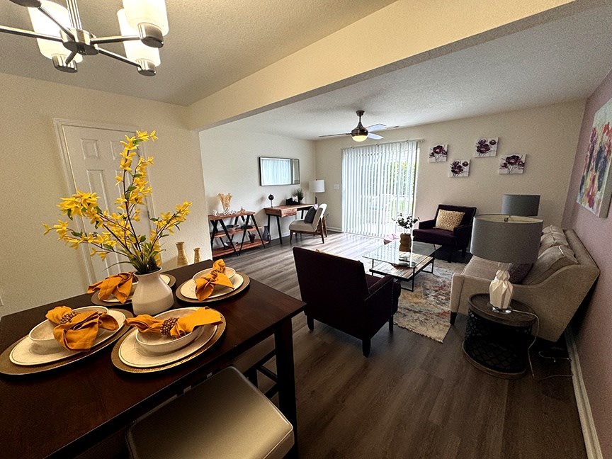 A dining room with a table set for four and a couch.