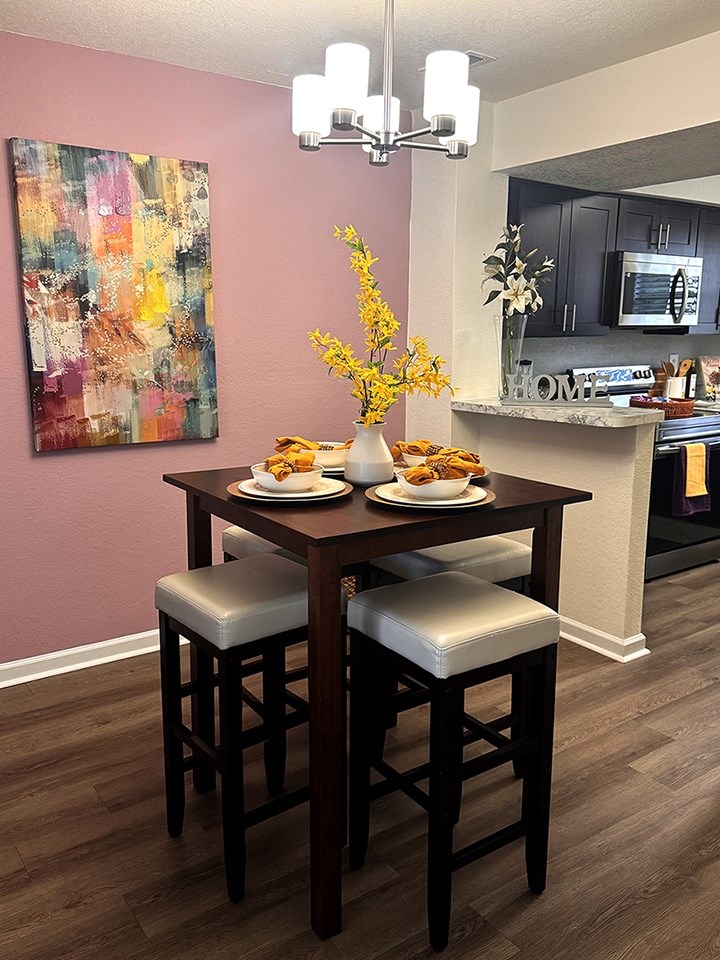 A dining table with two chairs and a vase of flowers on it.