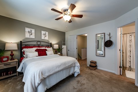 A bedroom with a large bed and a ceiling fan.